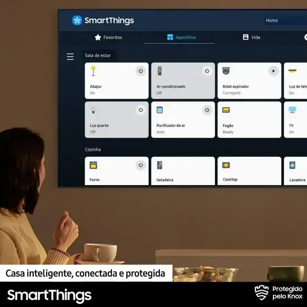 Imagem frontal da TV, com fundo neutro que destaca a tela do aplicativo.